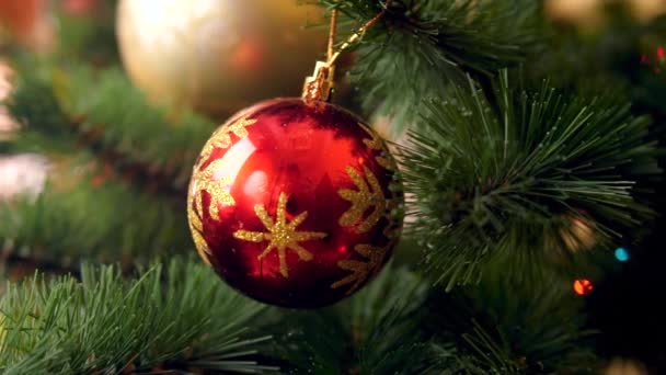 4K πλάνα από κόκκινο μπαλάκι και γιρλάντες σε όμορφο χριστουγεννιάτικο δέντρο. Τέλεια βολή για τις χειμερινές σας διακοπές και γιορτές — Αρχείο Βίντεο