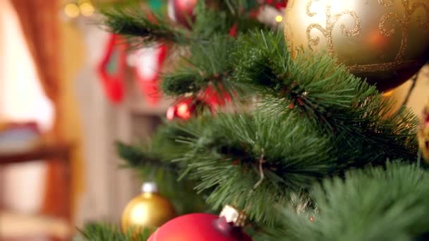 4k imagens de jovem mulher pendurado bugigangas douradas em galhos de árvore de Natal . — Vídeo de Stock
