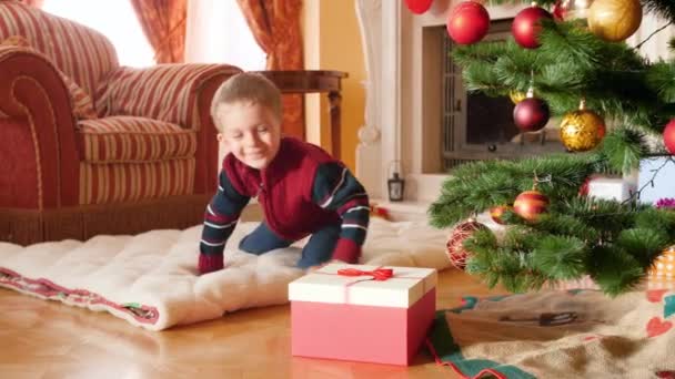 幸せな笑顔の小さな男の子の4kビデオは、サンタクロースから彼のクリスマスプレゼントを開き、おもちゃの列車を取ります。冬の休日やお祝いにプレゼントやプレゼントを受け取るお子様 — ストック動画