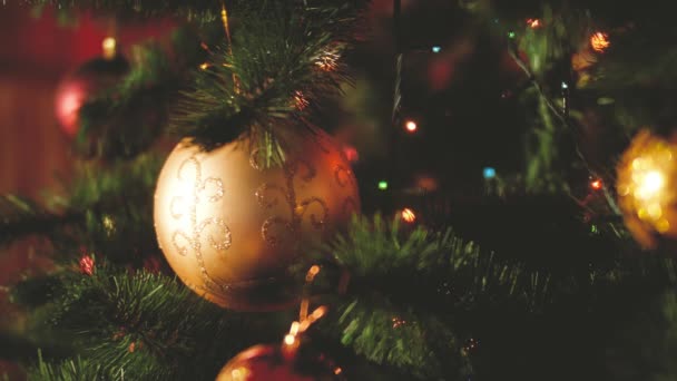 クリスマス前夜のクリスマスツリーにぶら下がっているボール、花輪、ライトのクローズアップトーンのビデオ。あなたの冬の休日やお祝いのための完璧なショット — ストック動画