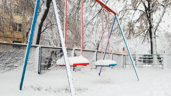 Bliska strzał pusty śnieg zadaszony plac zabaw po Blizzard. Dwa huśtawki pod śniegiem — Zdjęcie stockowe