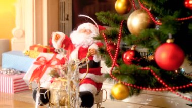 Oturma odasında şömine yanında dekore Noel ağacı altında Noel Baba bebek Closeup 4k görüntüleri. Kış kutlamaları ve tatiller için mükemmel çekim