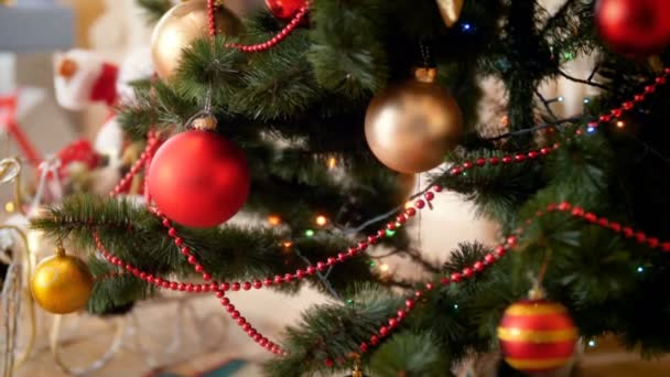 家の荒廃したクリスマスツリーにぶら下がっている美しいきらめくボーブルとライトのクローズアップ4k映像。冬のお祝いや休日のための完璧なショット — ストック動画