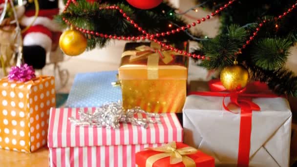 カラフルな贈り物やプレゼントの4Kトラッキングショットは、リビングルームでクリスマスツリーの下に横たわって、クリスマスライトを輝かせます。冬のお祝いや休日のための完璧なショット — ストック動画