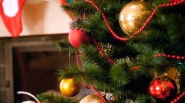 Noel ağacı dallarında asılı güzel takılara doğru yavaşça hareket eden kameranın 4K görüntüsü. Kış kutlamaları ve tatiller için mükemmel bir çekim.