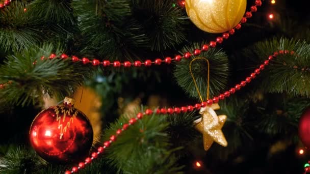 Closeup 4k panning vídeo de câmera se movendo ao longo de ramos de árvore de Natal com miçangas, bolas, brinquedos e guirlandas leves. Tiro perfeito para celebrações de inverno e feriados — Vídeo de Stock
