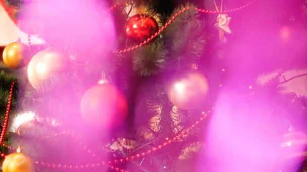 Primer plano 4k vídeo abstracto de brillante y brillante garlnd rosa delante del árbol de Navidad decorado. Perfecto para celebraciones de invierno y días festivos — Vídeo de stock