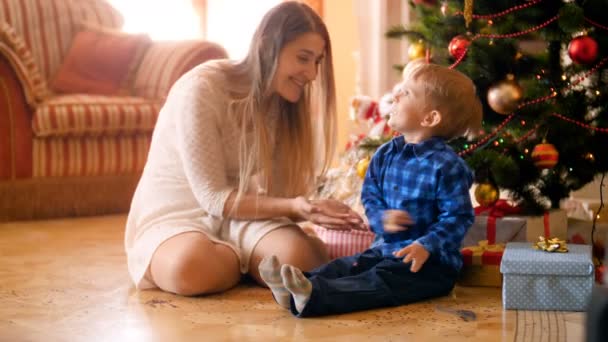 Des images 4k d'un petit garçon heureux avec une jeune mère jouant et jetant des confettis colorés et des paillettes. Famille avoir du bon temps et de plaisir pendant les vacances d'hiver et les célébrations . — Video