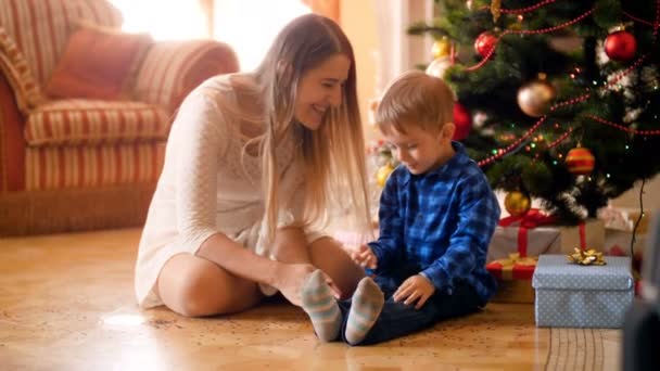 Vidéo 4k de joyeux petit garçon avec sa mère lançant des confettis de Noël colorés. Famille avoir du bon temps et de plaisir pendant les vacances d'hiver et les célébrations . — Video