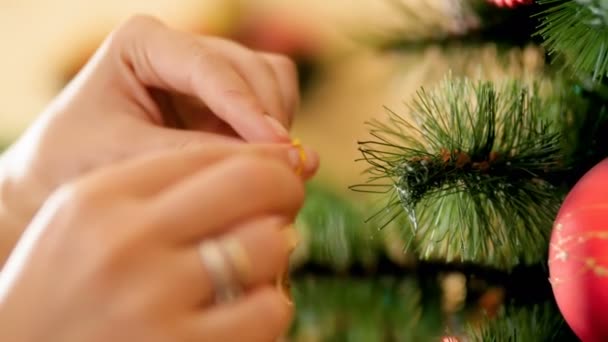 Close-up 4k video van jonge vrouw putting decoratieve sierlijke ster op kerstboom tak. Familie voorbereiden en decoreren huis op Winter vakantie en feesten. — Stockvideo