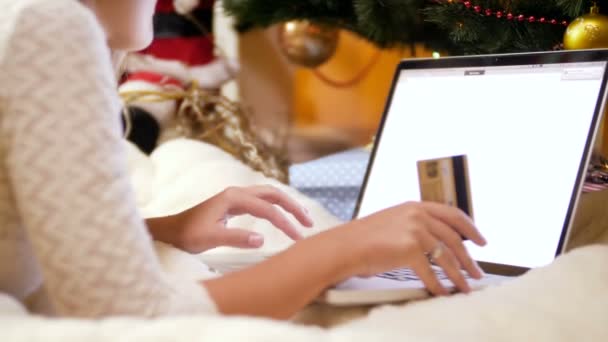 Closeup 4k video of young woman lying on blanket next to Christmas tree and ordering gifts and present online. Concept shot of online shopping and e-commerce. — Stock Video