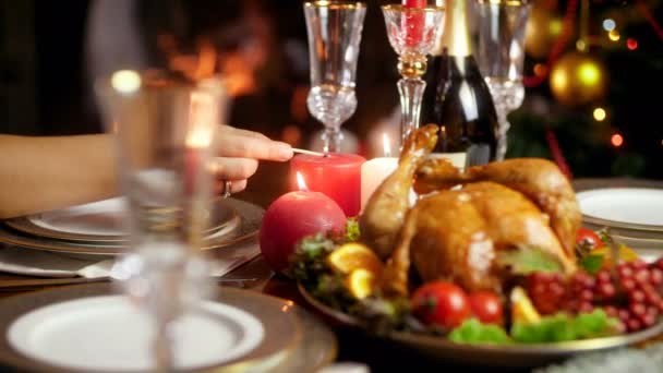 4k Video einer Frau, die Kerzen auf dem Tisch anzündet, die zum Weihnachts- oder Neujahrsessen serviert werden. Esstisch für große Familie an Winterfeiertagen und Feiertagen. — Stockvideo