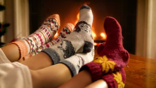 Closeup 4k footage of family wearing woolen socks holding feet next to fire in fireplace. People relaxing on winter holidays and celebrations at home — Stock Video