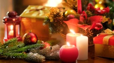 Renkli süs eşyaları, hediyeler ve Santa ve Cristmas çelenk hediyeler ile kutuları karşı mum yakma Closeup 4k video. Kış kutlamaları ve tatiller için mükemmel çekim