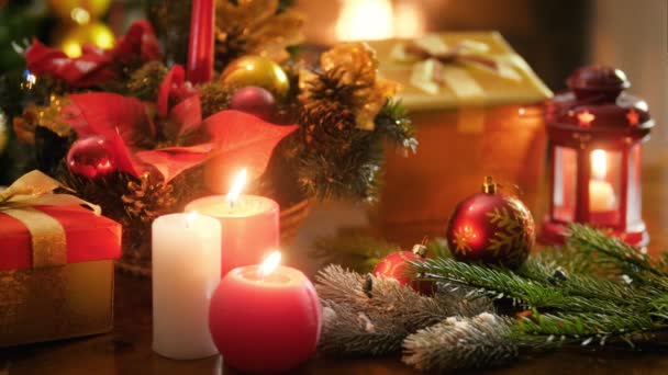 Closeup vídeo 4k de velas em chamas na mesa de madeira contra decorações de Natal e fogo em chamas no fogo. Tiro perfeito para celebrações de inverno e feriados — Vídeo de Stock