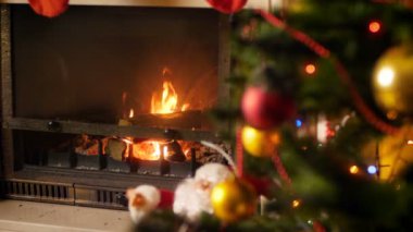 Parlayan renkli ışıklar ile dekore Edilmiş Noel ağacı yanında şömine yanan yangın 4k video. Kış kutlamaları ve tatiller için mükemmel çekim