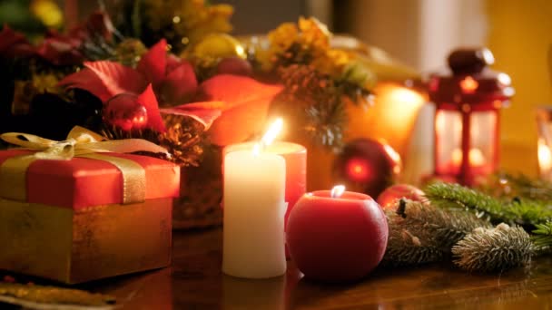 Close up 4k video of burning candles and traditional Christmas decorations on table at living room. Идеальный кадр для зимних праздников и праздников — стоковое видео