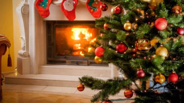 Noel ağacının güzel bir görüntüsü. Işıkları ve mücevherleri oturma odasında yanan şömine karşısında.