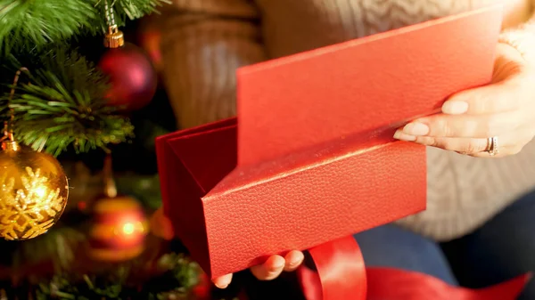 Closeup image of woman opens Christmas gift under Xmas tree — ストック写真