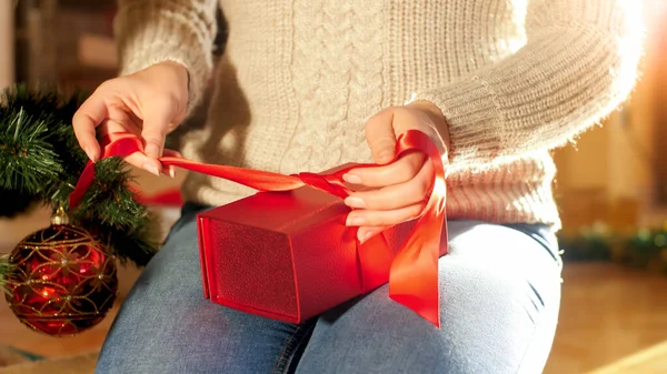 Close-up foto van jonge moeder die kerstcadeaus voor haar kinderen inpakt. Vrouw strikken lint doos op huidige doos. — Stockfoto