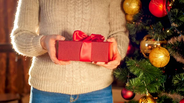 Closeup image young woman holding red Christmas gift box with big ribbon bow — ストック写真