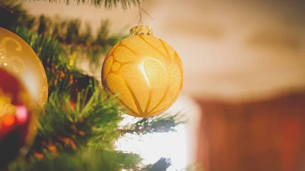 Tonad jul bakgrund. Gyllene grannlåt hängande på julgranen mot stort fönster — Stockfoto