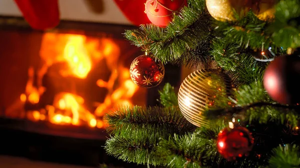 Beautiful background of burning fireplace and decorated Christmas tree with baubles and garlands — Stock Photo, Image
