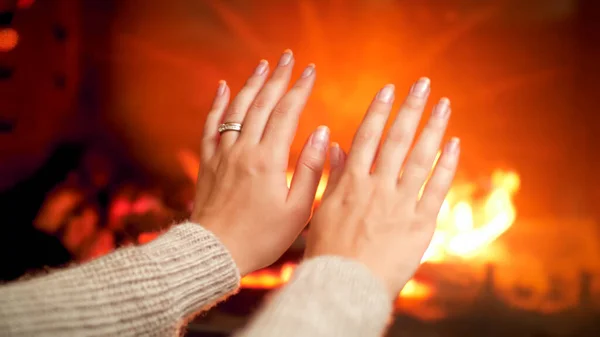 Closeup photo of woman with cold hands stretching them to the burning fireplace — Stock Photo, Image