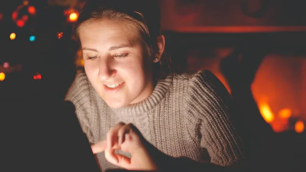 Closeup tonificado retrato de coruja sorridente usando tablet na noite de Natal ao lado da lareira ardente — Fotografia de Stock