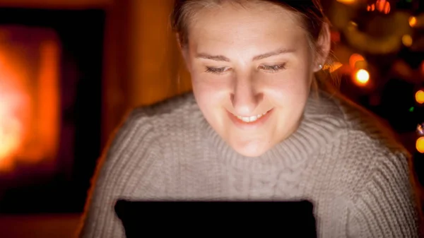 Szekrény portré boldog mosolygós nő digitális tabletta ül a kandalló éjjel — Stock Fotó