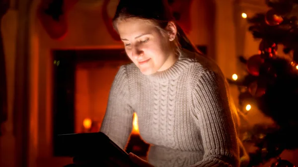 Πορτρέτο της νεαρής γυναίκας με πουλόβερ που κάθεται δίπλα στο τζάκι και χρησιμοποιεί ψηφιακή ταμπλέτα — Φωτογραφία Αρχείου