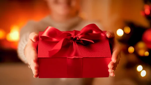 Imagem de close-up de jovem segurando em mãos bela caixa vermelha para presente de Natal ou presente com grande laço de fita — Fotografia de Stock