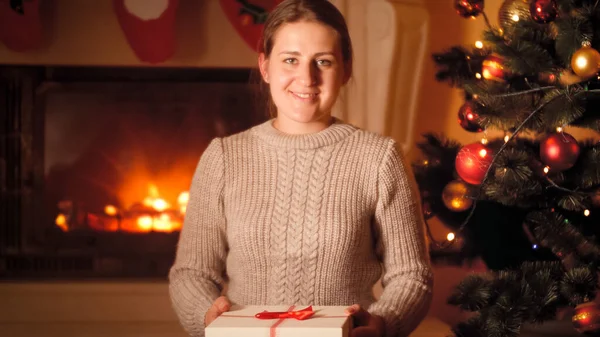 Retrato de una hermosa mujer joven en una caja de suéter de lana con regalo de Navidad y mirando a la cámara —  Fotos de Stock