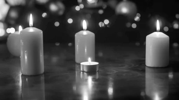 Closeup imagem preto e branco de velas em chamas na mesa de madeira contra bokehs luz — Fotografia de Stock