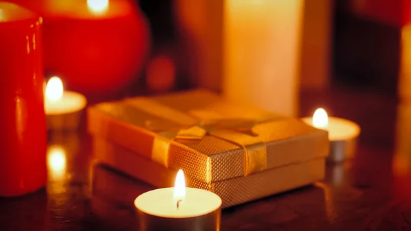 Imagen de primer plano de velas encendidas y caja pequeña dorada con regalo para Navidad — Foto de Stock