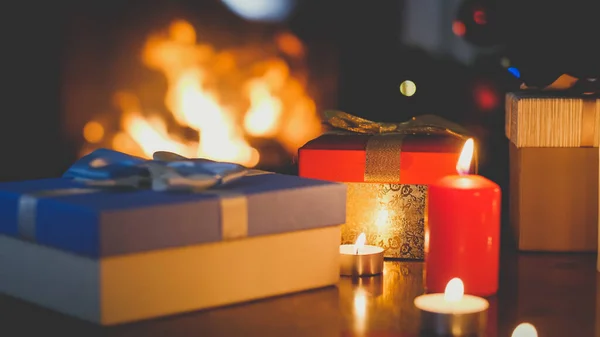 Imagine tonifiată de închidere a cutiilor cu cadouri de Crăciun și lumânări aprinse împotriva focului în șemineu — Fotografie, imagine de stoc