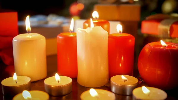 Detailní záběr na spoustu bílých a červených hořících svíček na dřevěném stole v obývacím pokoji — Stock fotografie