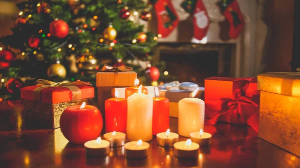 夜に輝くクリスマスツリーと暖炉に対してサンタからのろうそくや贈り物を燃やすの美しいトーンイメージ — ストック写真