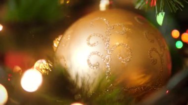 Noel ağacında parıldayan Led lambalı altın mücevher topunun 4K görüntüsü.