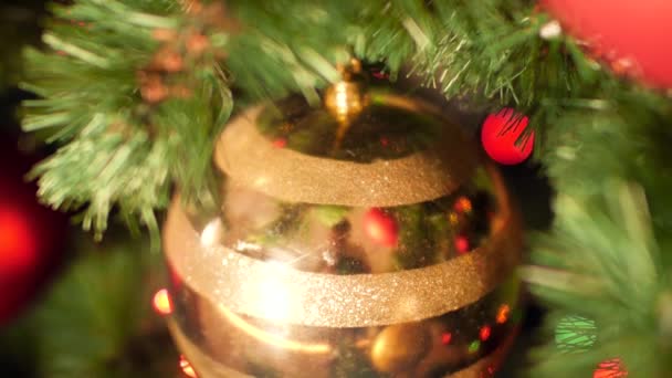 Närbild panorering video av gyllene bollar, grannlåt och kransar dekorera julgran hemma — Stockvideo