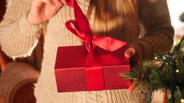 Запись крупным планом в 4К, где женщина открывает красную коробку с подарком и заглядывает внутрь. Перфект, снятый к Рождеству или Новому году — стоковое видео