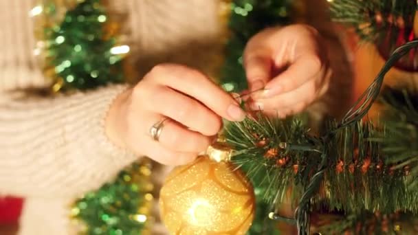 Primer plano 4k video de mujer joven decorando árbol de Navidad con bolas y guirnaldas por la mañana — Vídeo de stock