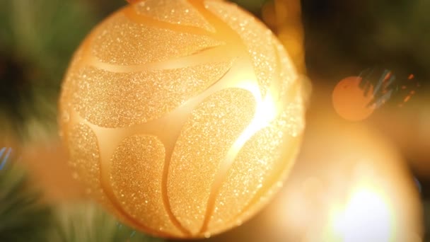 4k video of beautiful golden ball with glitters hanging on Christmas tree branch — Stock Video