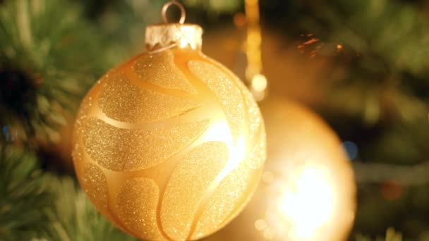 Macro video of beautiful golden baubles and glowing lights on Christmas tree — Stock Video