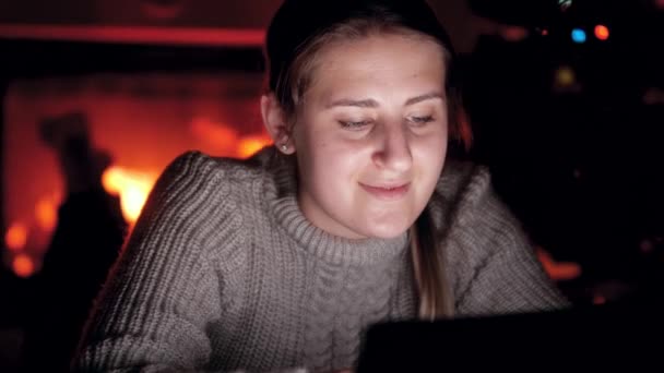 4k портрет молодой женщины в свитере с помощью цифрового планшета ночью в гостиной с горящим огнем — стоковое видео