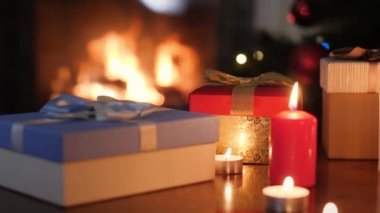 İçinde Noel hediyeleri olan kutular ve mumlar olan 4K video oturma odasındaki şömine ateşine karşı. Noel veya Yeni Yıl için mükemmel bir arkaplan veya arkaplan