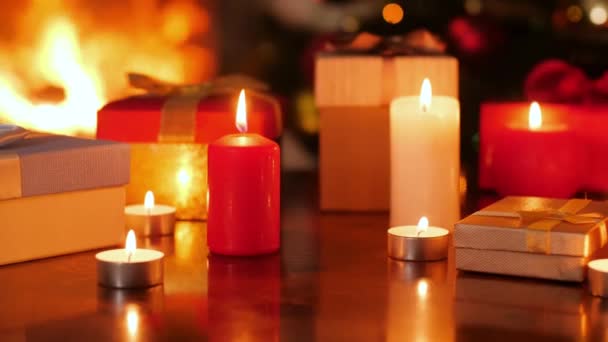 4k телесные кадры горящих свечей и коробок с рождественскими подарками в гостиной с огнями и елкой — стоковое видео