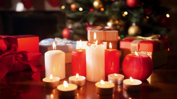 4k primer plano de vídeo de velas de adviento y regalos de Navidad en la mesa de madera contra el brillante árbol de Navidad — Vídeo de stock