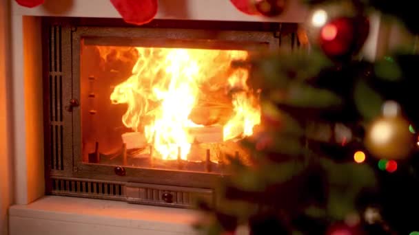 4k footage of burning fireplace next to decorated CHristmas tre at house — Stock Video