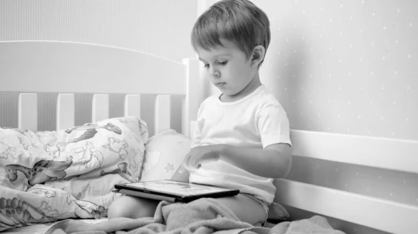 Ritratto in bianco e nero di un bambino che usa un tablet digitale prima di andare a letto — Foto Stock